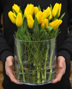 Flower arrangement with 15 yellow tulips in glass vase