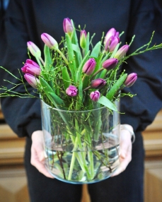 Flower arrangement with 15 purple tulips in glass vase