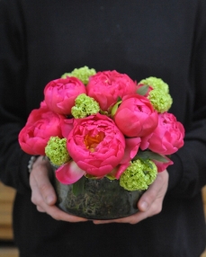 Flower arrangement with peonies and viburnum in glass bowl 