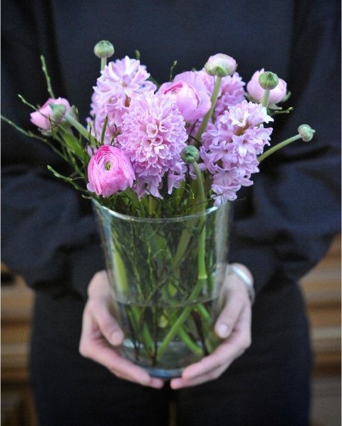 Flower arrangement with pink hyacinth and ranunculus in glass vase